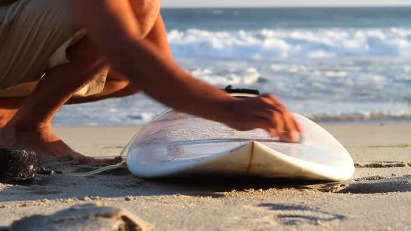 A surfer waxing board before surfing