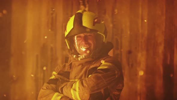 Portrait of Young Firefighter in Front of Burning House Smiling in Full Uniform