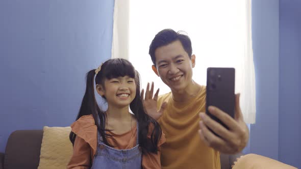 Asian Family of Father and Daughter Taking a Selfie Photo with Mobile Phone at Home