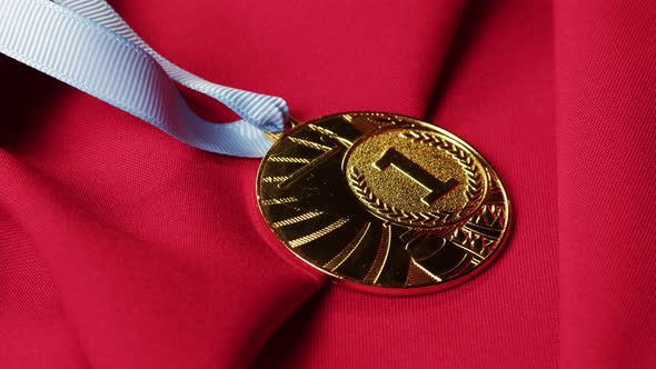 Gold Medal with Ribbon on Red Background Closeup