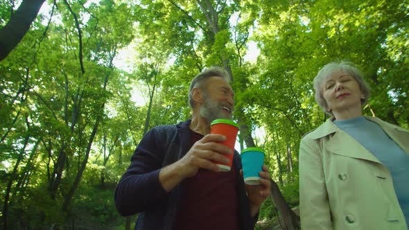 Portrait of Happy Smiling Mature Man with Cups Running Up to Woman