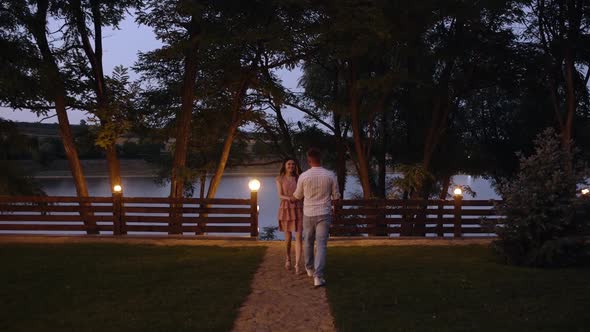 The Happy Young Woman Hugs Her Boyfriend and They Go Together To a Lake.