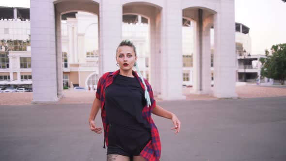 Young Stylish Funky Girl with Green Hair Riding Roller Skates and Dancing in Park Slow Motion