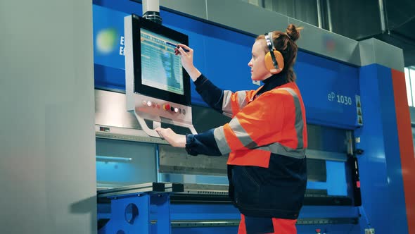 Workwoman Operating a Metal Bending Machine Through a Screen