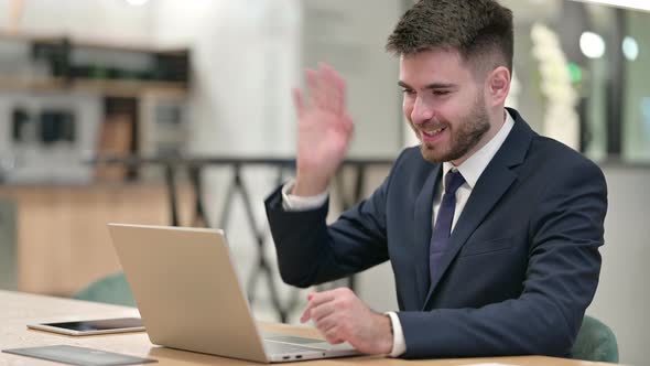 Cheerful Young Businessman Talking on Video Call on Laptop in Office 