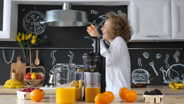 Happy Girl Dancing And Making Fresh Orange Juice At Kitchen