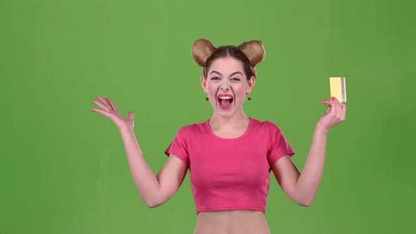 Teen in a Pink Topic with a Credit Card Is Happy. Green Screen. Slow Motion