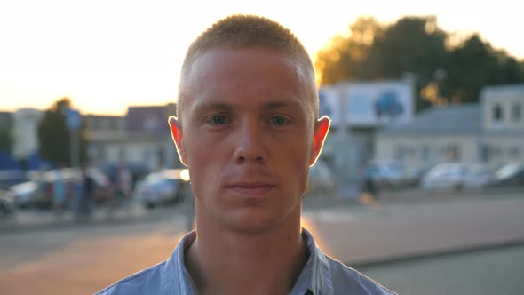 Portrait of Young Serious Businessman in Shirt Looking Into the Camera Against the Background