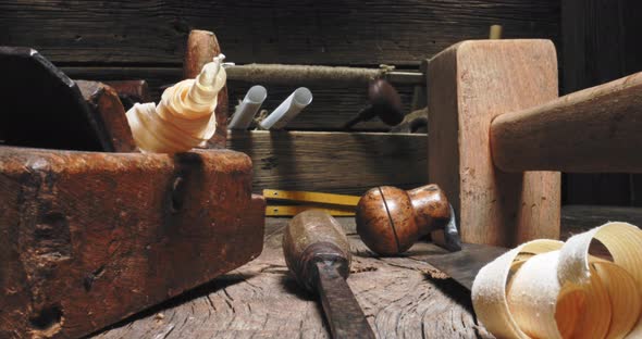 Tampers, chisels, planes in carpentry workshop. Vintage joinery workbench.