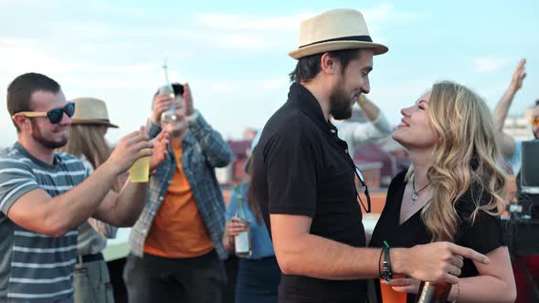 Beautiful Young Couple Laughing and Passionately Kissing at Summer Rooftop Party