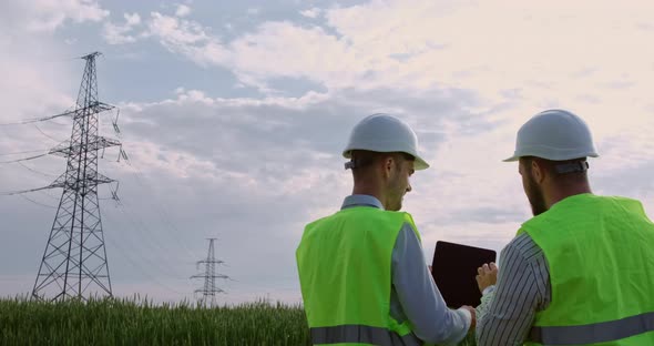 Power engineers work against the background of electric poles.