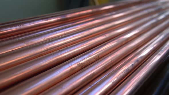 Metal, copper, plumbing pipes stack with shiny reflections at warehouse.