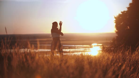 Woman with Long Braids Slowly Dancing on Sunset Field