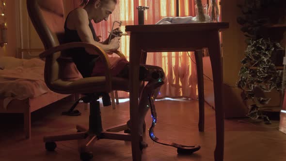 Young Man with Leg Prosthesis and Dreadlocks Works at Table