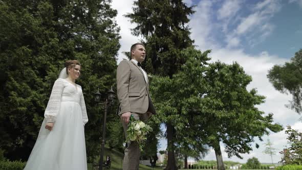 Newlyweds. Caucasian Groom with Bride Walking in Park. Wedding Couple. Man and Woman in Love