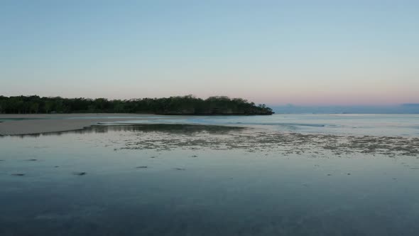 Low tide in Natadola Bay in Fiji with glassy water surface reflecting clear sky