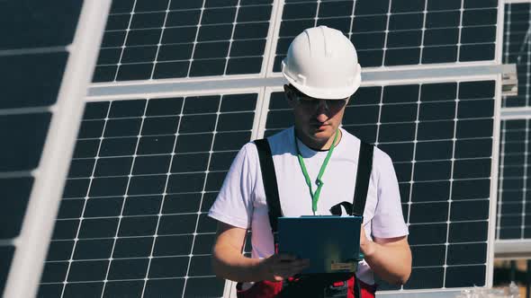 Solar Energy Specialist Examining Solar Panels with His Tablet in a Solar Park. Solar Energy Concept