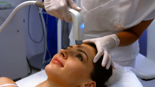 Doctor performing laser hair removal on female patient face