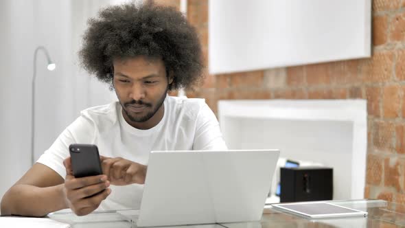 African Man Using Smartphone and Laptop