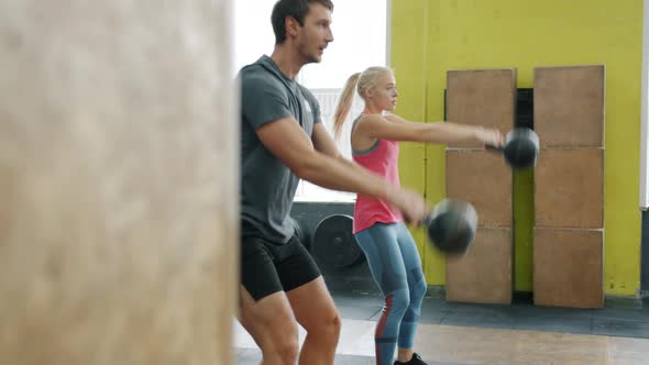 Man and Woman Squatting and Lifting Weight in Crossfit Gym Focused on Exercise