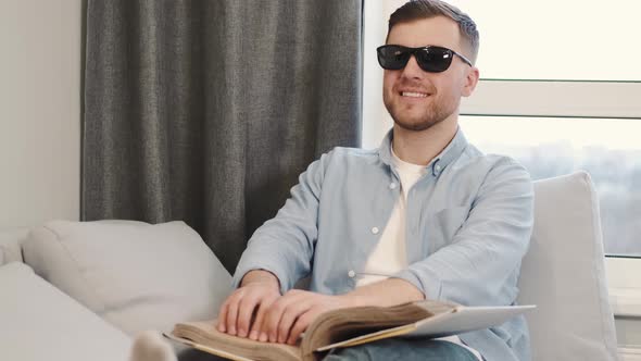 Blind Young Man Reading Braille Book on Couch