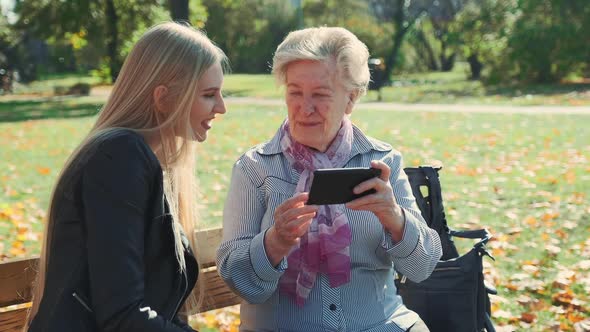 Elder Grandmother Showing Her Granddaughter Photos on Smartphone