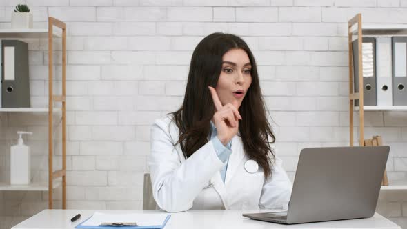 Happy Female Doctor Having Great Idea Using Laptop In Office