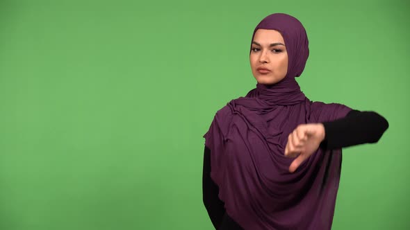 A Young Beautiful Muslim Woman Shows a Thumb Down to the Camera and Shakes Her Head  Green Screen