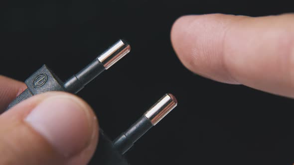 Man Shows European Plug in Black Plastic Case at Darkness