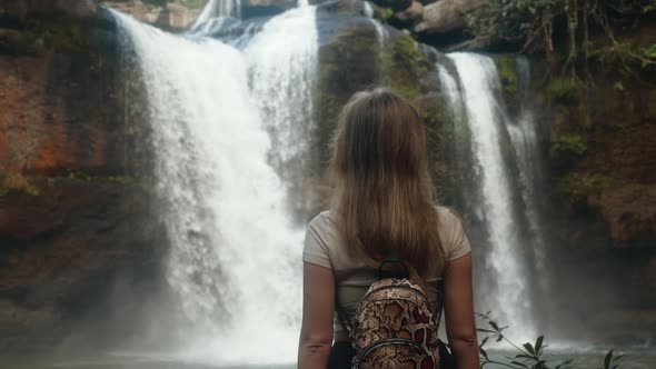 Rear View of Young Travel Woman Standing in Front of Waterfall