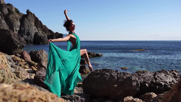 Side View a Young Beautiful Sensual Woman with Black Hair in a Long Mint Dress Posing on a Beach