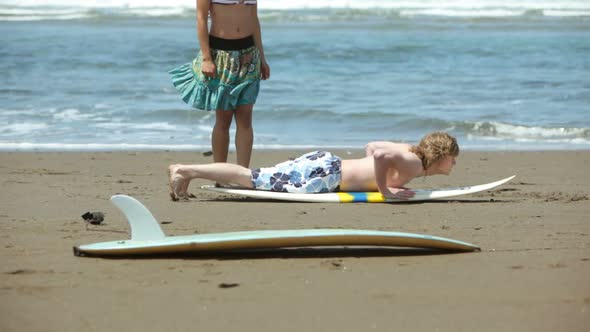 Young man teaching woman how to surf