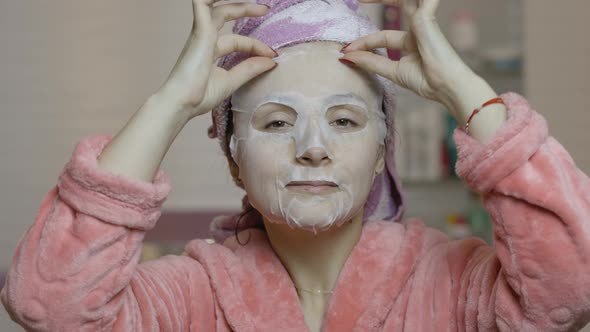 Woman Applying Cosmetic Face Mask in Bathroom. Skincare Spa. Facial Mask