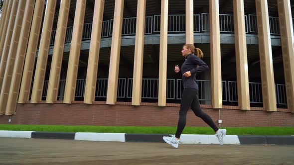 Fit woman jogging around building in city