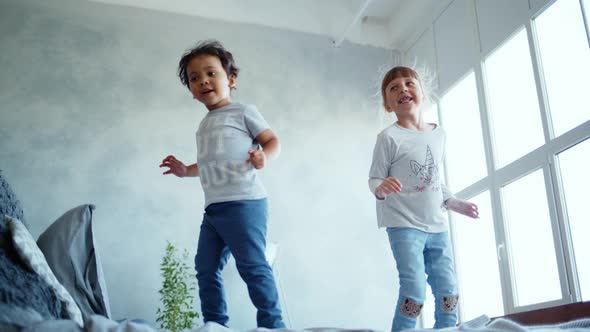 Happy Family at Home. Little Children Are Jumping on the Bed in the House.