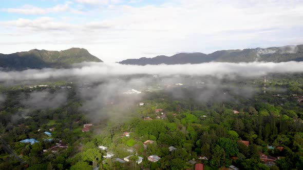 Lower clouds over homes in Valle de Anton town in central Panama extinct volcano crater, Aerial pan