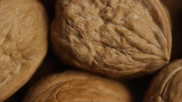 Cinematic, rotating shot of walnuts in their shells on a white surface - WALNUTS