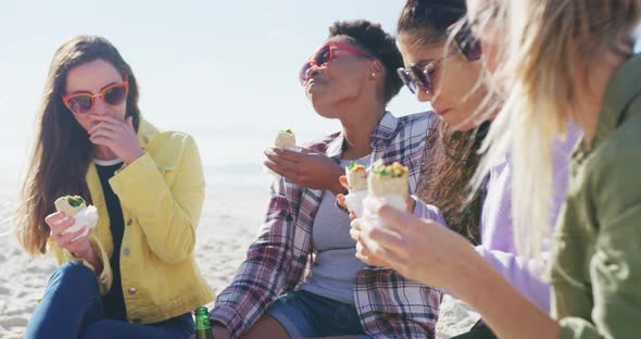 Happy group of diverse female friends having fun, having picnic at the beach