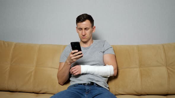 Man Scrolls Through Social Media with Forearm in Gypsum Band