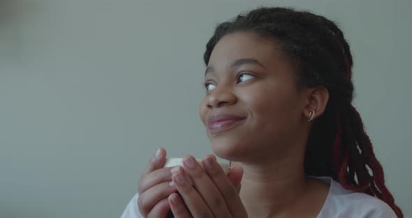 Attractive Young African Woman Smiling and Drinking From a Cup