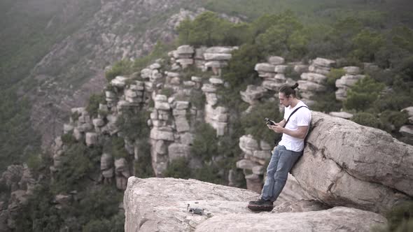 Caucasian Filmmaker Taking of a Drone on a Cliff While Chewing Gum