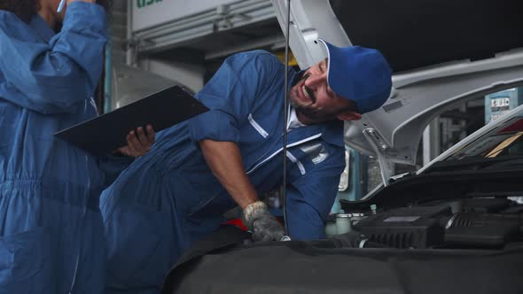 Mechanic man and woman in uniform checking diagnostic for fix and repair car together at garage.