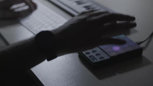 Close up on producer / musician hand hitting a MIDI drum pad and producing a beat in the studio