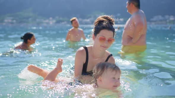 Asian Modern Mother Play Swim with Toddler Baby Boy in Tropical Sea