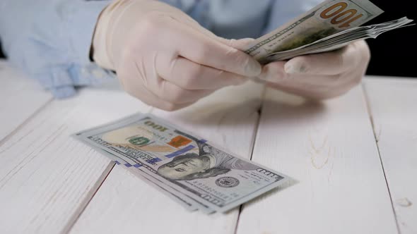 Closeup of a Woman in Gloves Counting Hundreddollar Bills