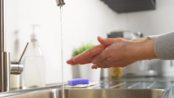 Woman Washing Hands with Liquid Soap in Kitchen