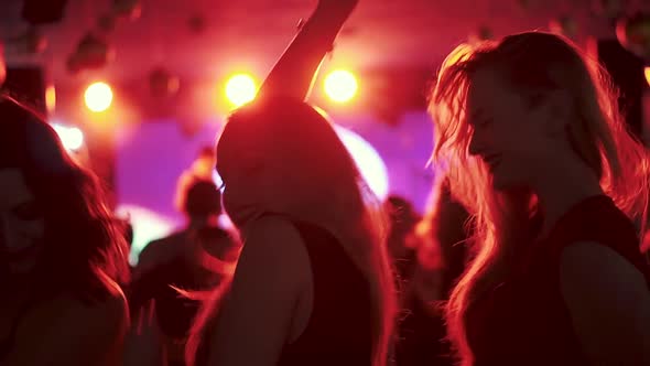 Friends Dancing in the Spotlight at a Disco in a Nightclub. Girls Dancing in a Crowd of People