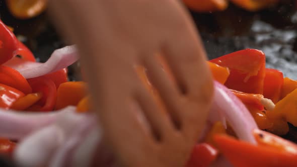 Stir frying onion and orange and red bell pepper. Slow Motion.