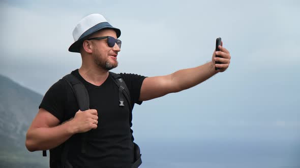 Hipster Male Travel Blogger Shooting Online Broadcasting Live Streaming on Mountain Peak Over Sea