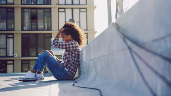 Fashionable young woman on urban rooftop using smartphone